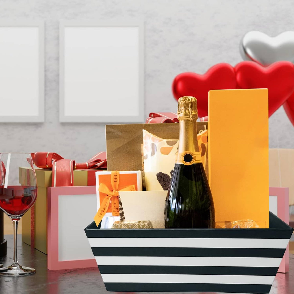 Black and white striped gift basket holding bottles and wrapped presents with bow