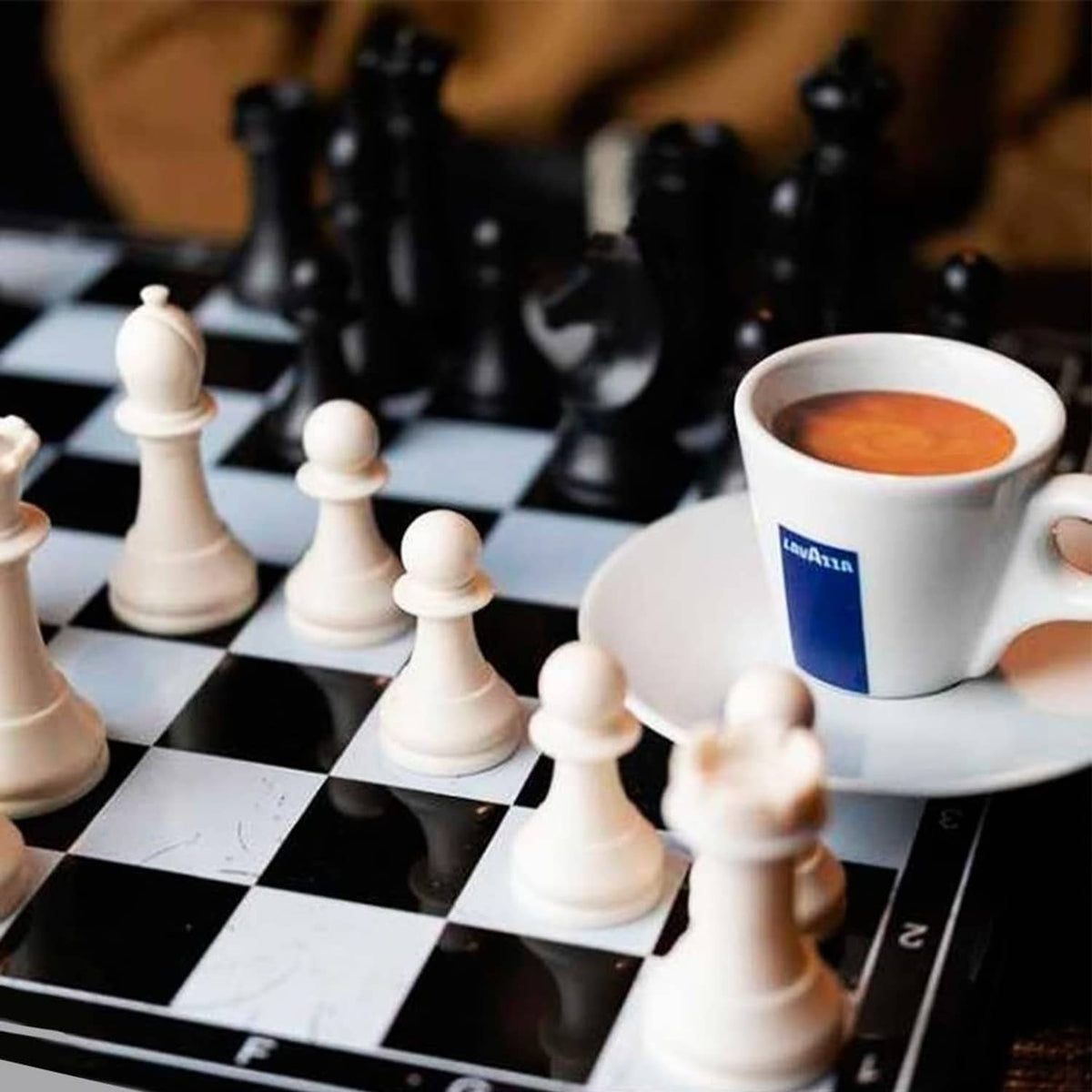 Lavazza coffee cup on a chessboard with chess pieces around it