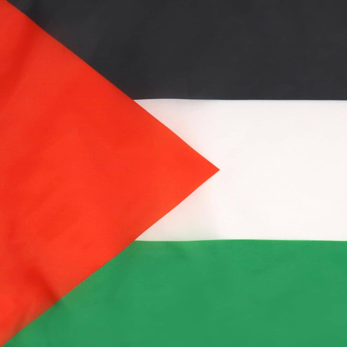 Close-up of Palestinian flag fabric: red triangle, black band, white stripe, green band