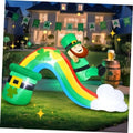 Inflatable rainbow slide with smiling leprechaun, green clover pot, and white clouds