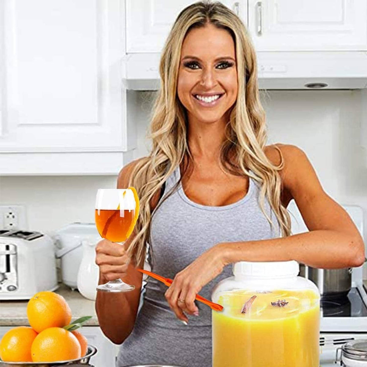 Plastic orange peeler tool held near oranges on the countertop, bright orange handle.