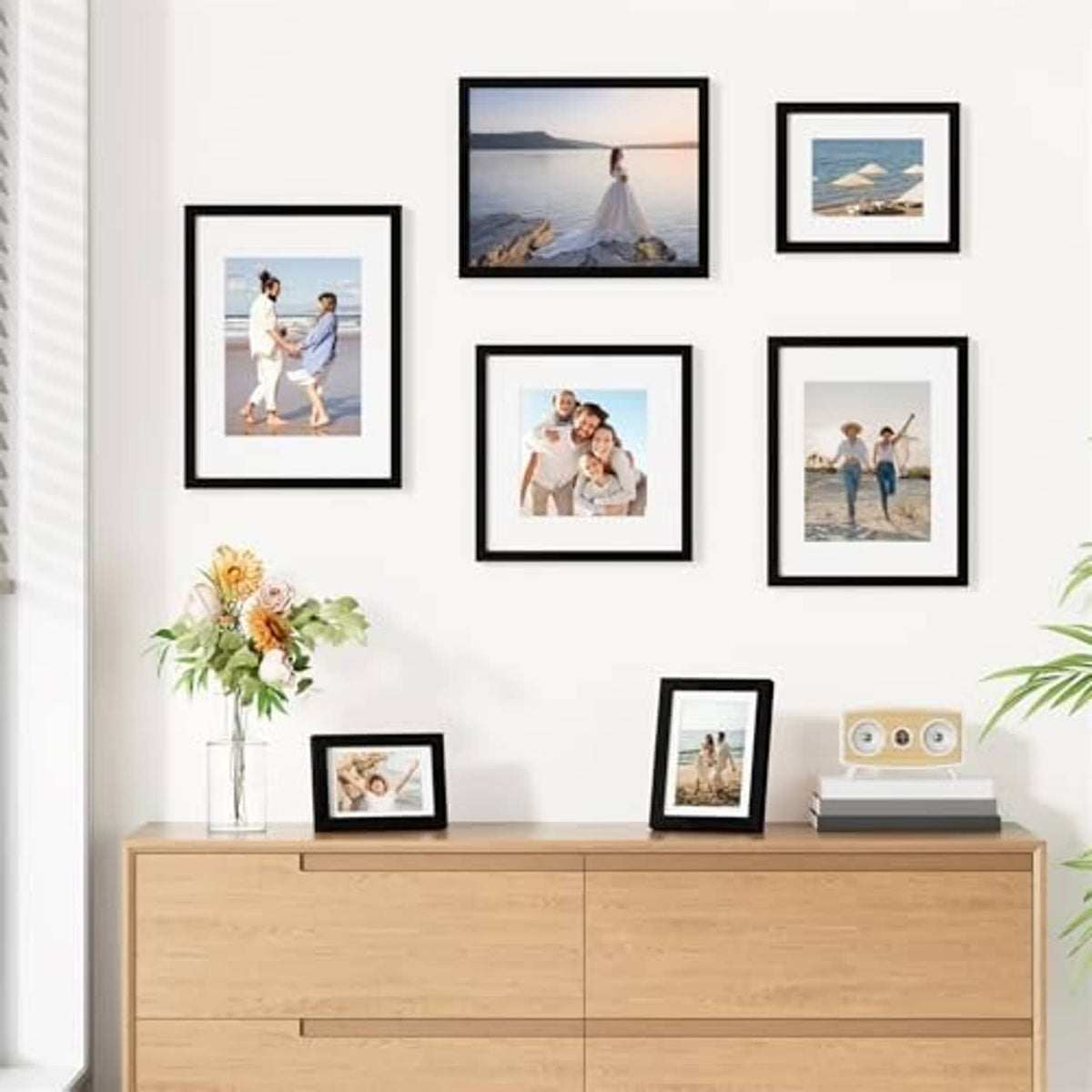 Black picture frame set of nine arranged on wall with assorted photo prints