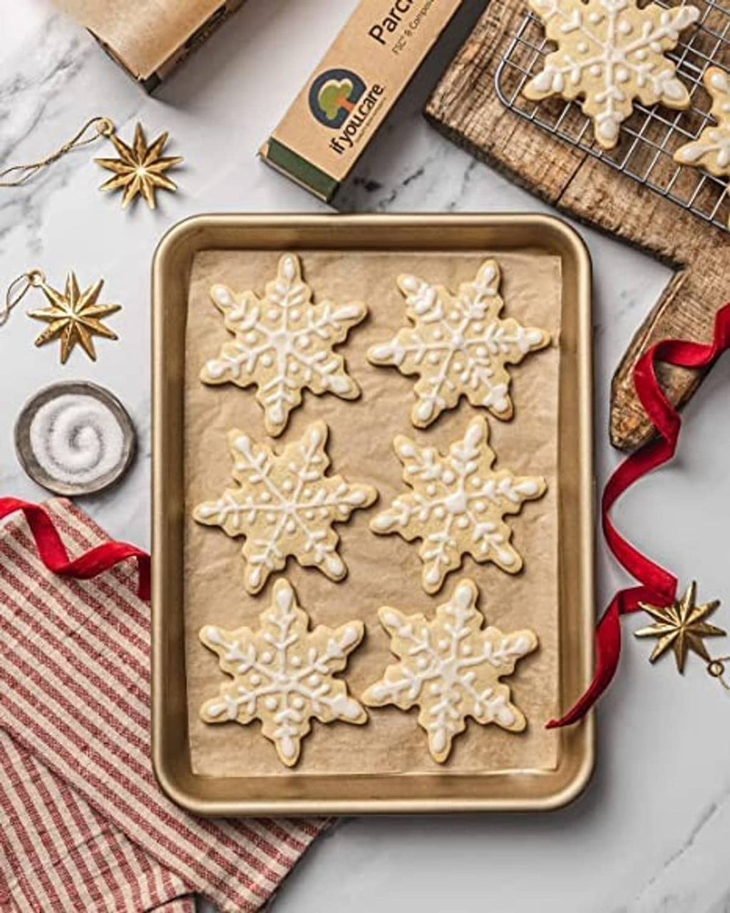 Parchment-lined baking tray with snowflake cookies, with parchment paper box