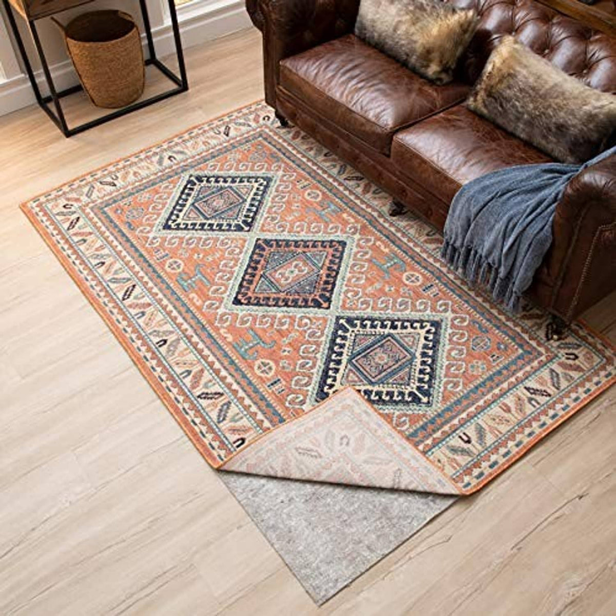 Light gray felt rug pad under a patterned area rug on light wood floor