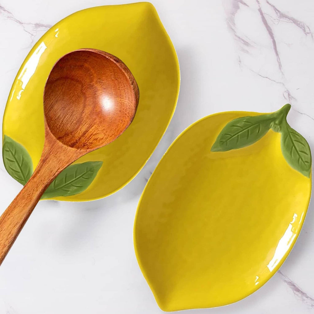 Yellow ceramic lemon-shaped spoon rest with dark wooden spoon and green leaf details