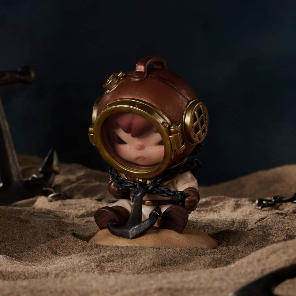 Tamed Hirono figure in a brown round helmet with goggles, sitting on a sandy base