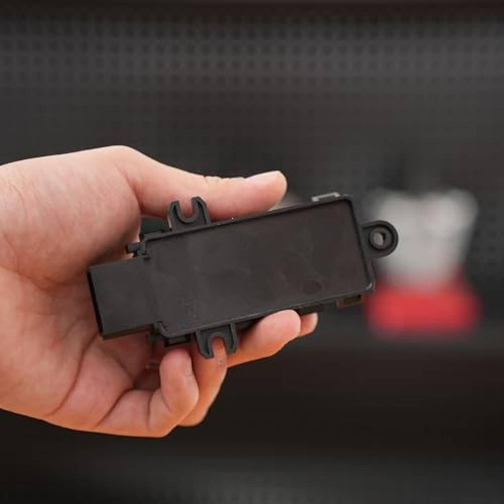 Black power seat switch module held in hand, flat face and mounting pins