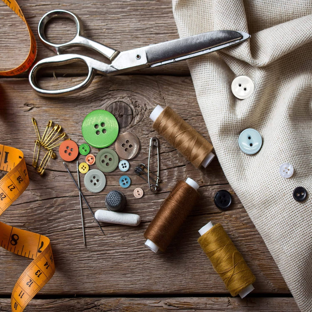 Mixed round resin buttons with thread spools and sewing tools on a wooden surface.