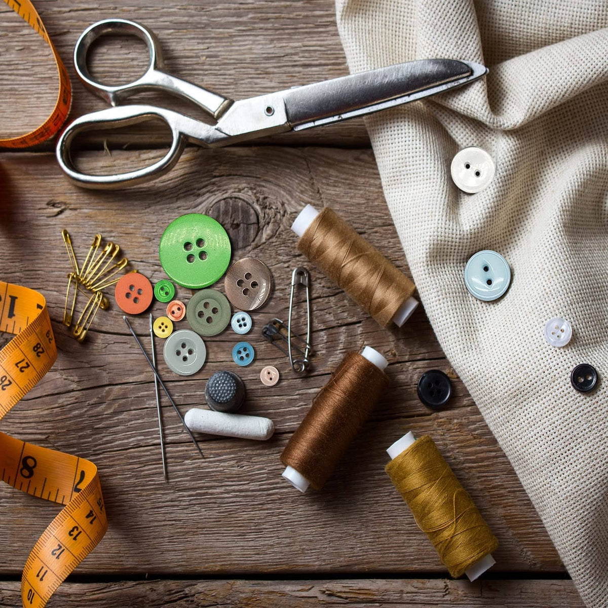 Mixed round resin buttons with thread spools and sewing tools on a wooden surface.