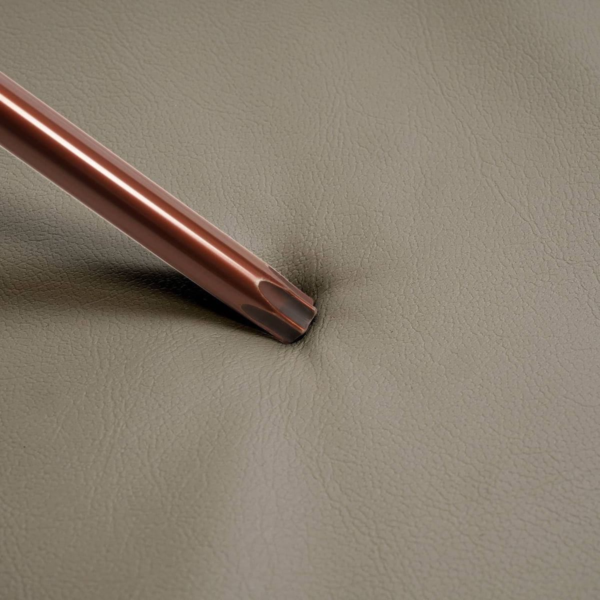 Tan seat cover edge with stitched trim, showing flexible faux-leather surface.