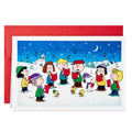 Holiday greeting card with Peanuts characters caroling in snowy night scene, red envelope