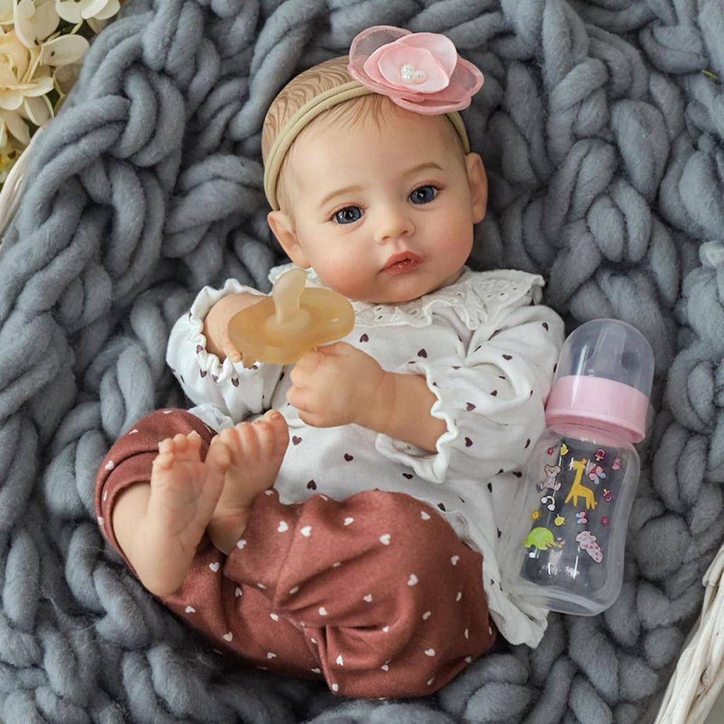 Realistic 18-inch reborn baby girl doll with headband, sipping from a baby bottle.