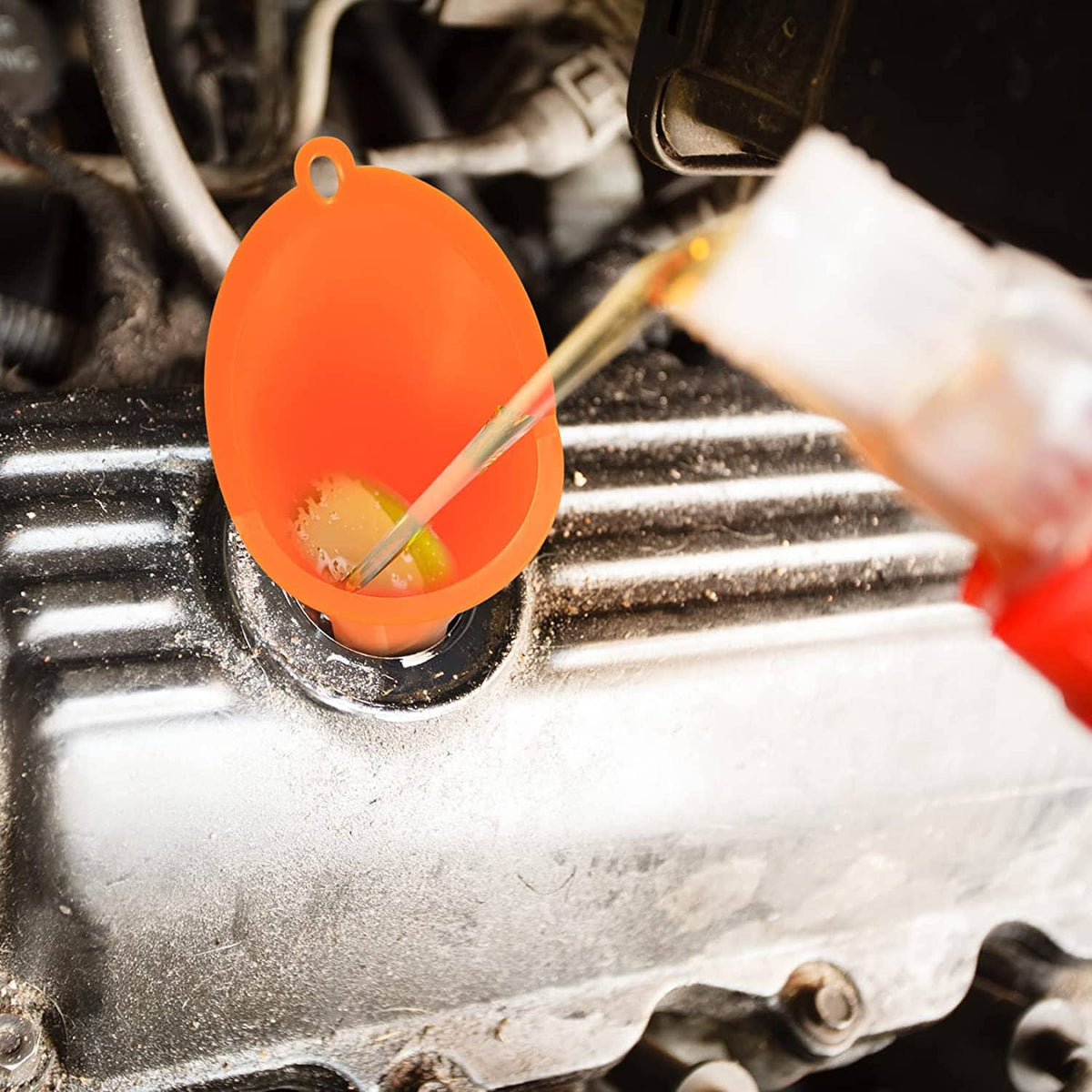 Orange funnel positioned at vehicle filler opening with oil drip control