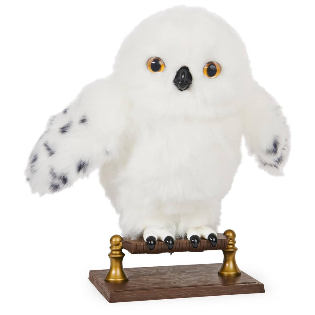White interactive owl plush with amber eyes, perched on a brown base with gold posts.