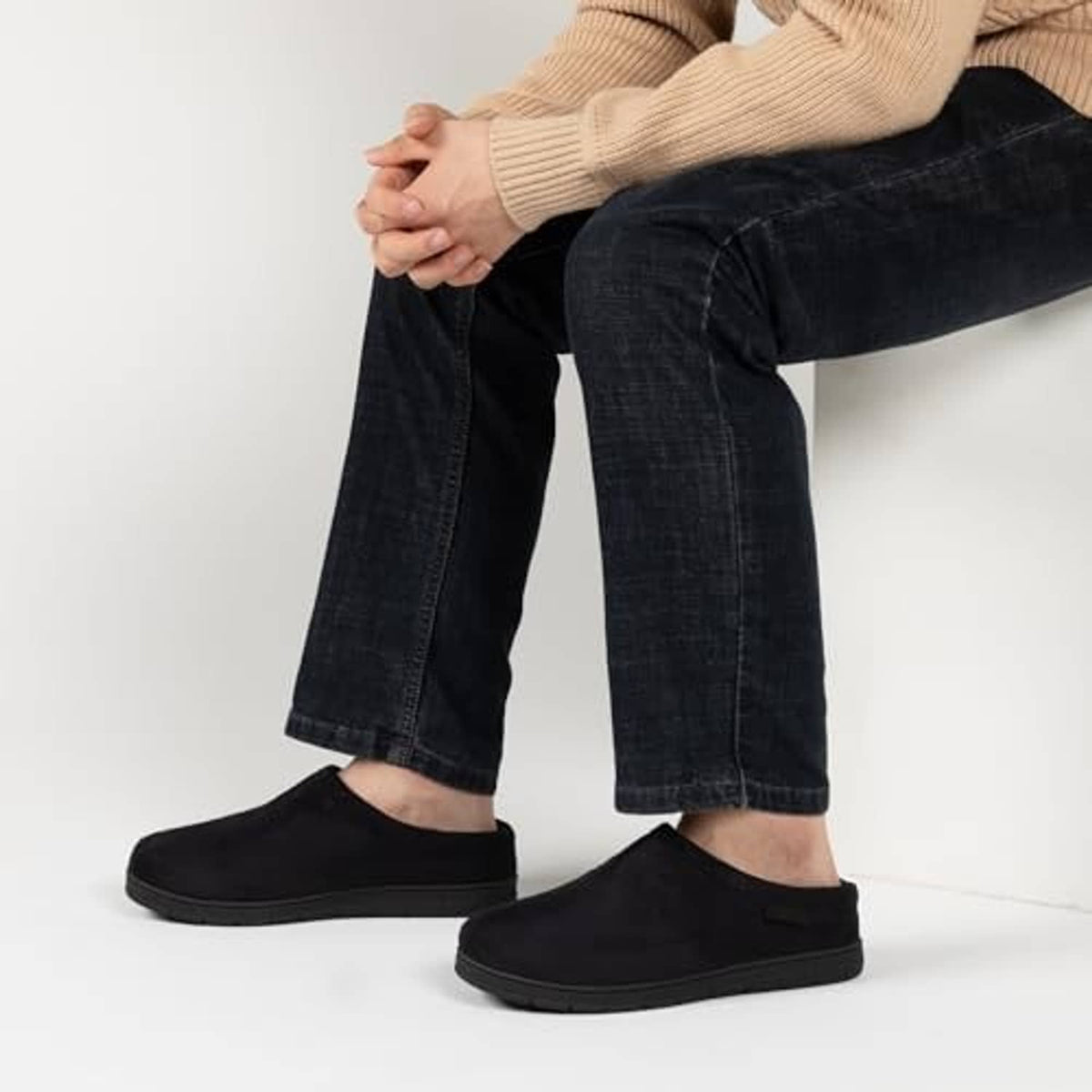 Black men's slip-on house slippers worn with jeans and socks, rounded toe