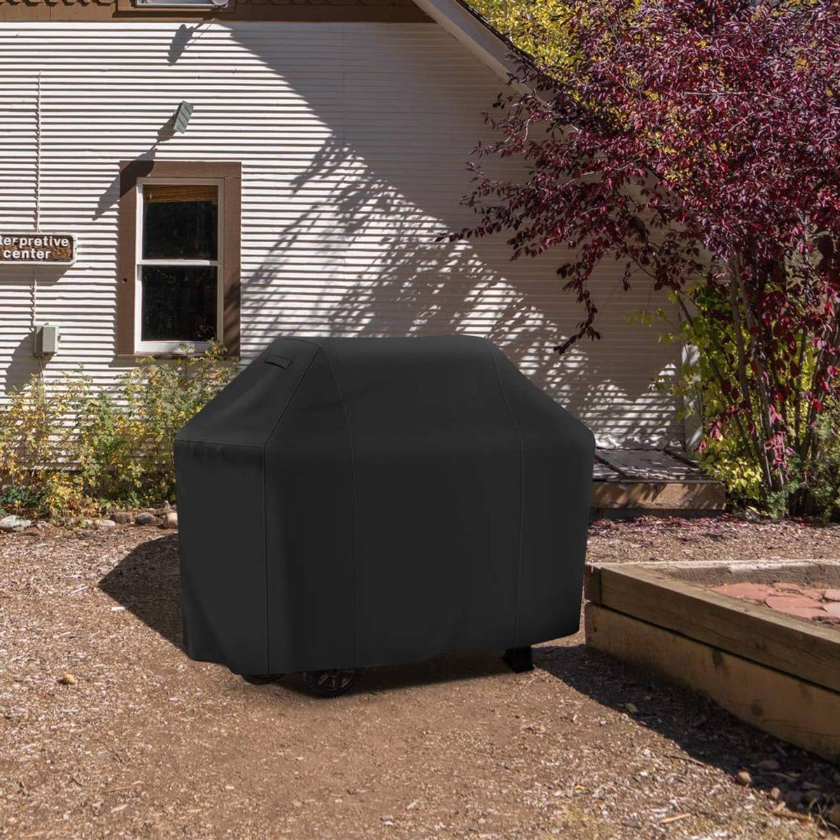 Black 55-inch grill cover protecting a gas barbecue grill outdoors