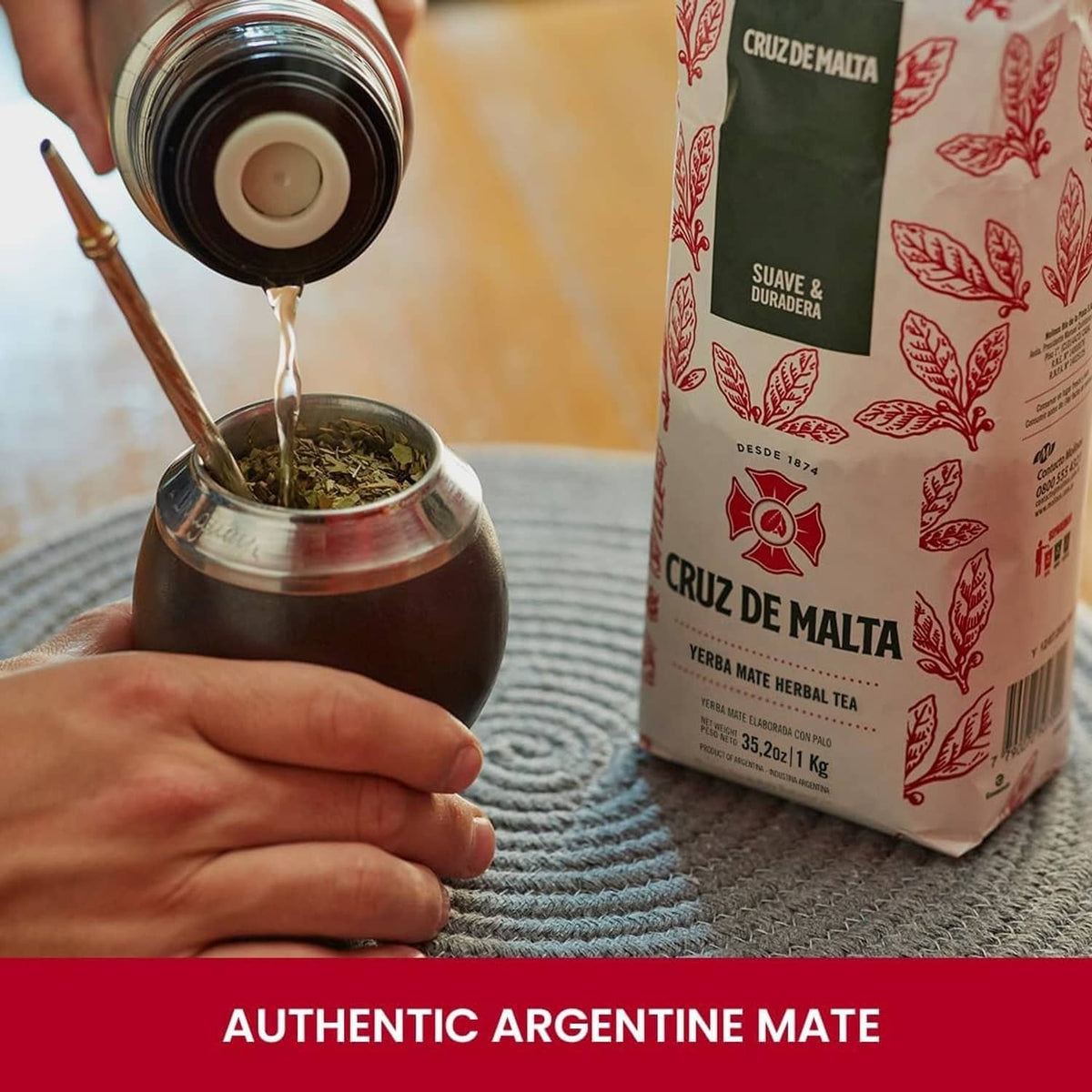 Yerba mate herbal tea pouch beside a cup of brewed drink and a metal bombilla