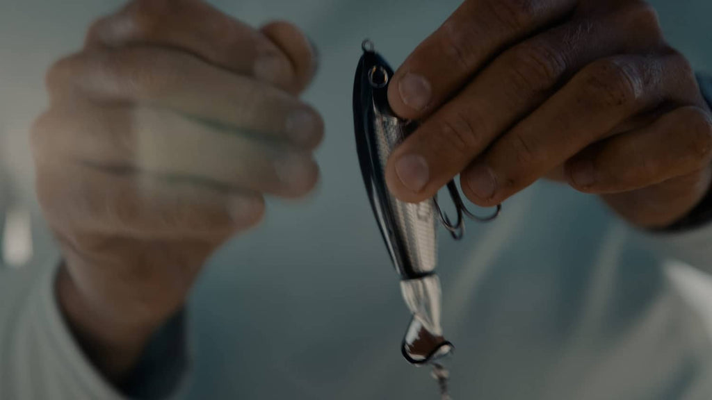 Hands holding a topwater fishing lure with treble hook