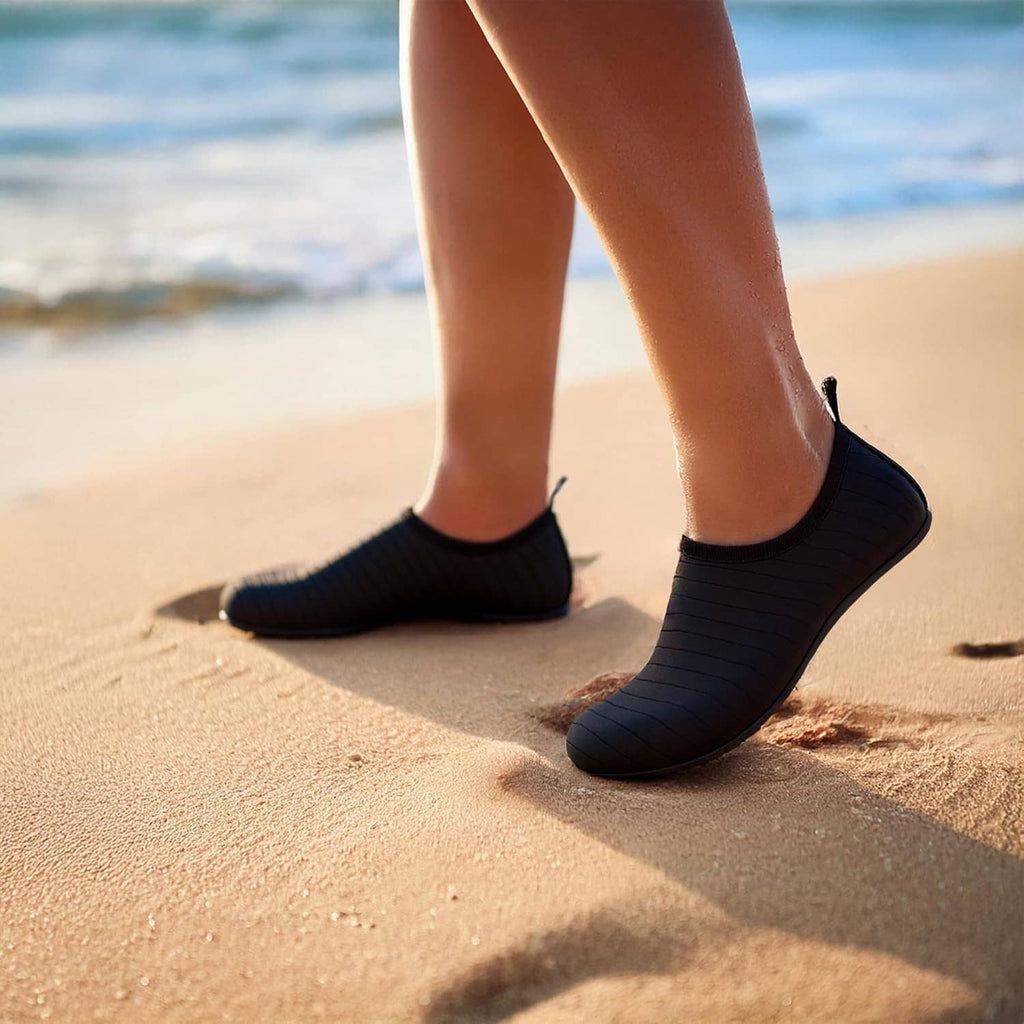 Black water sock shoes worn on feet on sandy beach