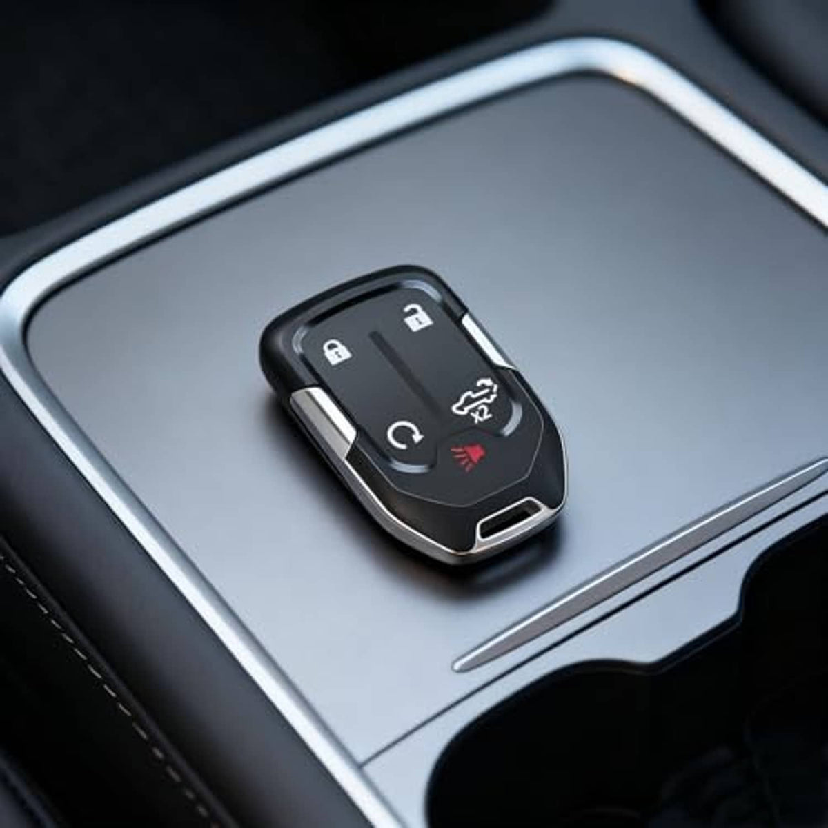 Black 5-button keyless remote key fob shell on a car console with button icons