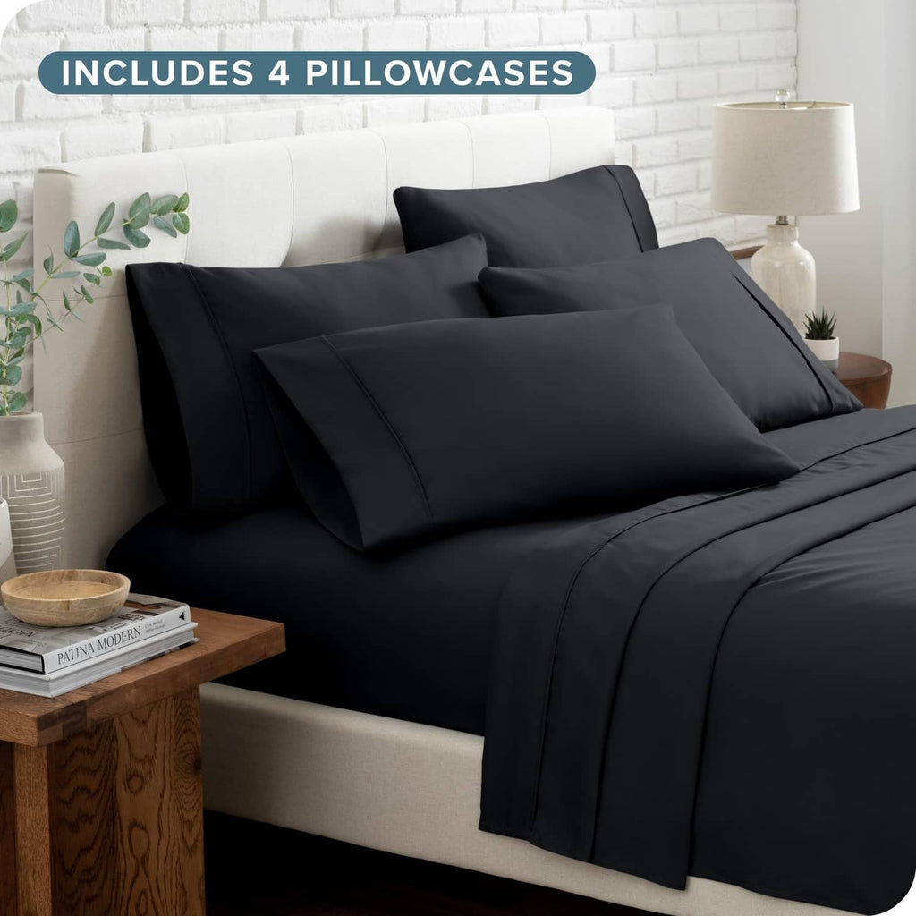 Black bed sheet set with four pillowcases on bed with folded top sheet.