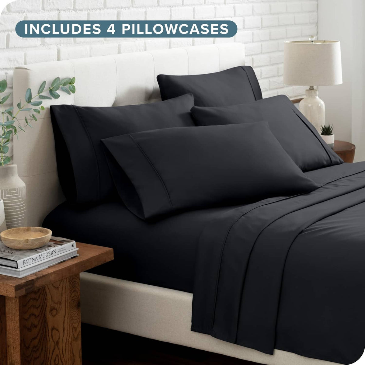 Black bed sheet set with four pillowcases on bed with folded top sheet.