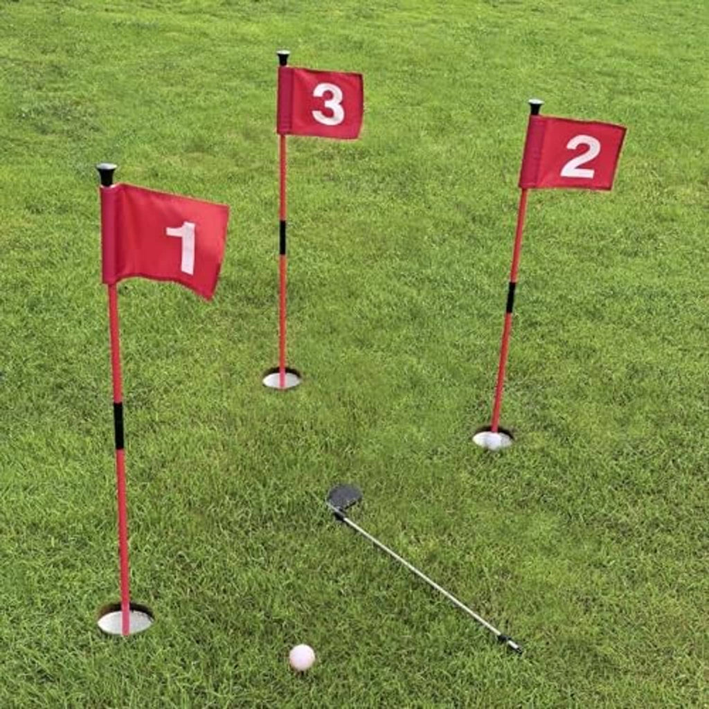 Three red practice golf flags with numbered banners on white poles and flat round bases