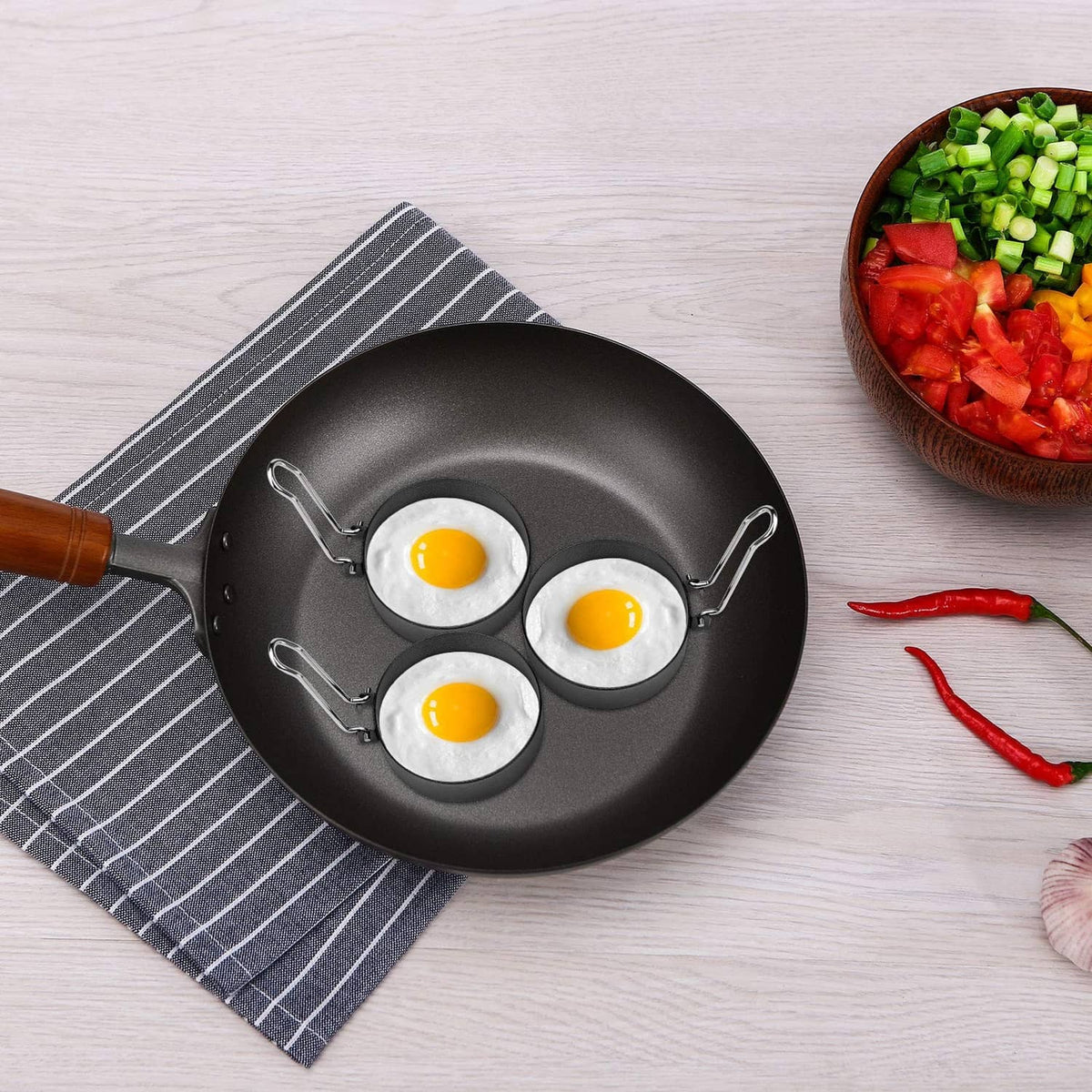 Nonstick skillet with three round egg cooking wells and three sunny-side eggs
