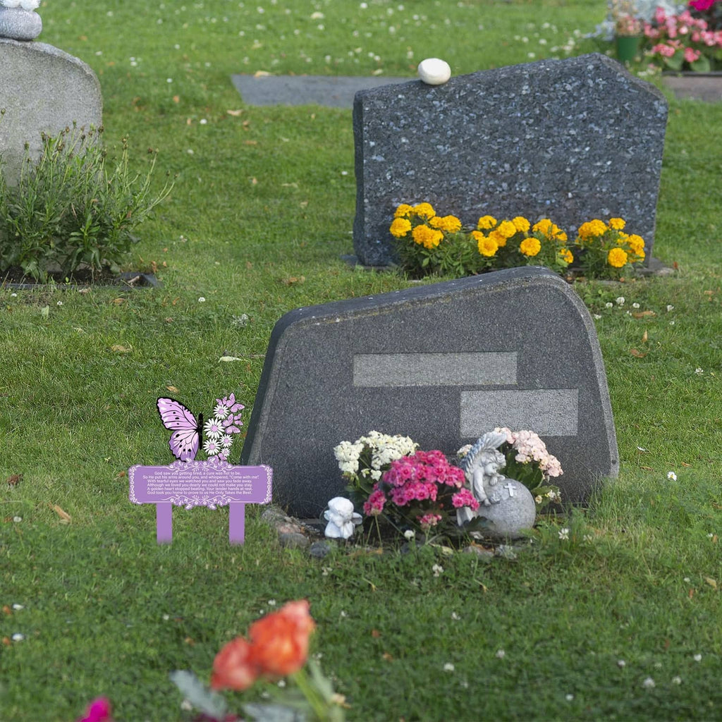 Purple grave memorial stake with butterfly and floral accents beside flowers