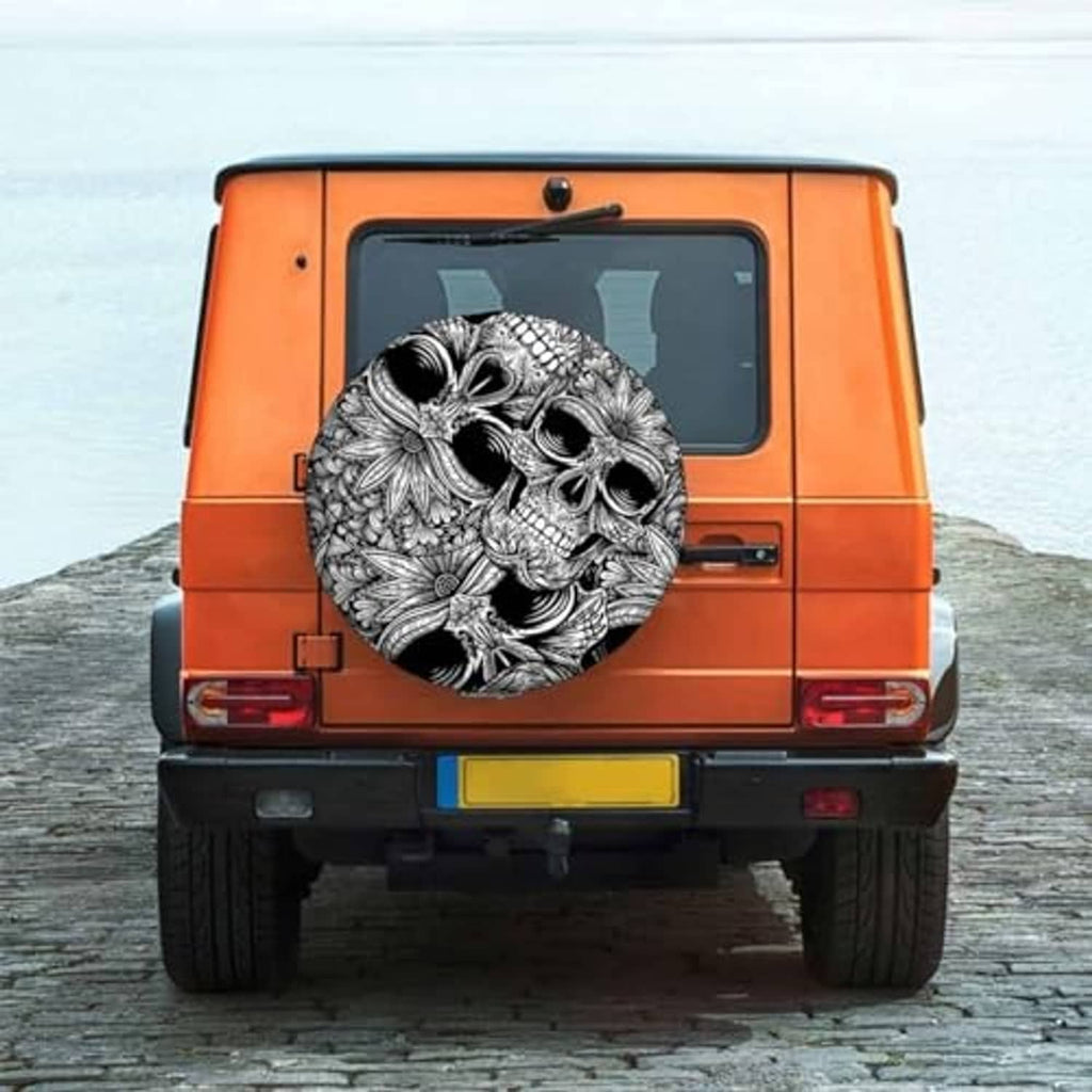 Skull spare tire cover on rear of orange truck, ornate black-and-white skull design
