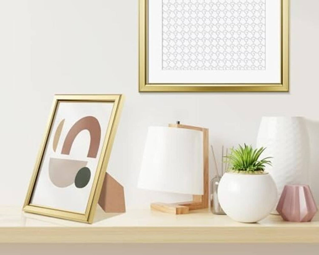 Gold picture frame on tabletop with white mat and abstract art