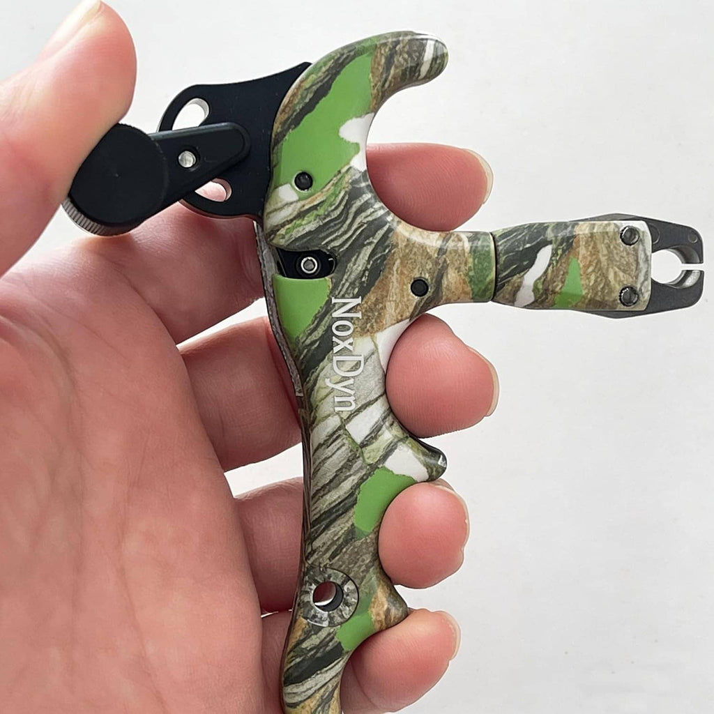Archery bow thumb release held in fingers, black trigger over green camo handle