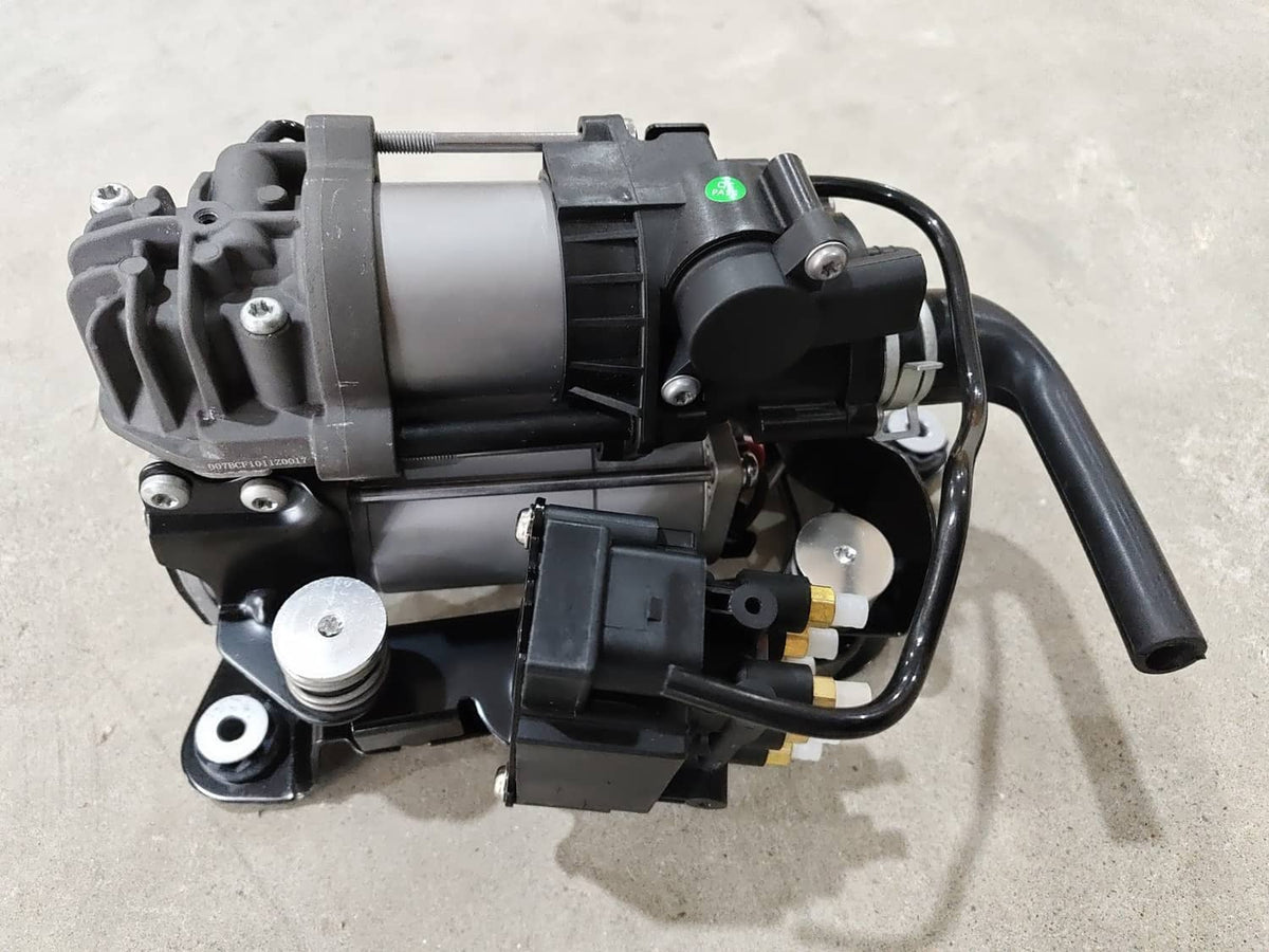 Air suspension compressor pump, side view with black housing, silver cylinder, wiring harness and fittings
