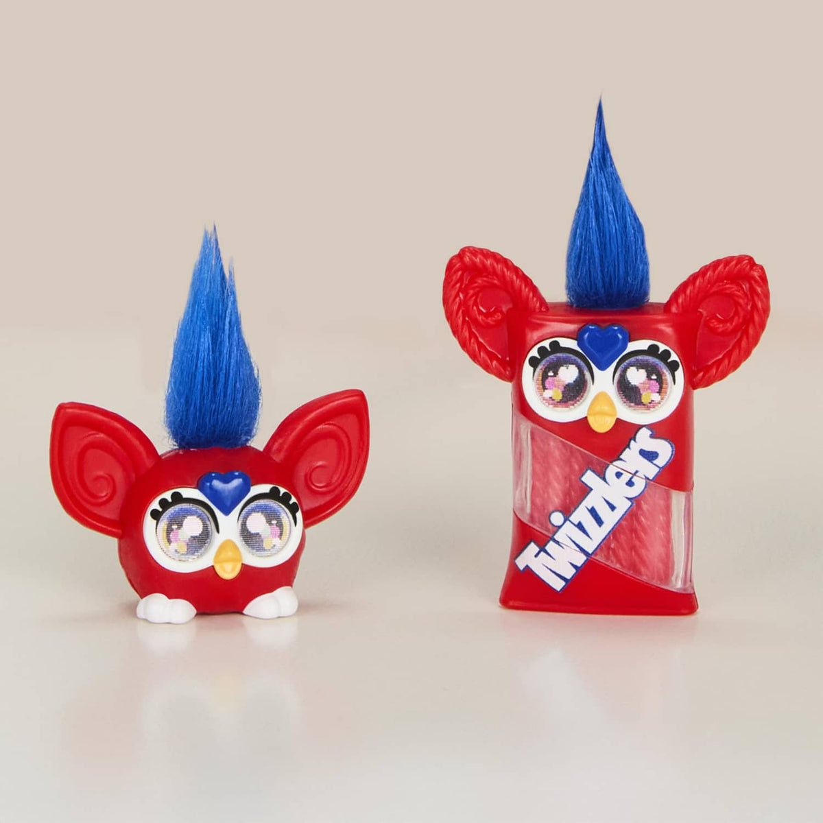 Two red Furby minis candy-themed figures with blue mohawks and heart-eyed goggles