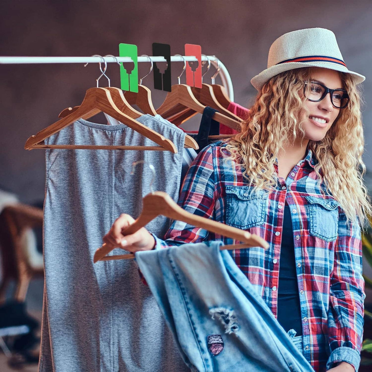 Woman adjusts colorful hanging closet dividers on a clothing rack with wooden hangers