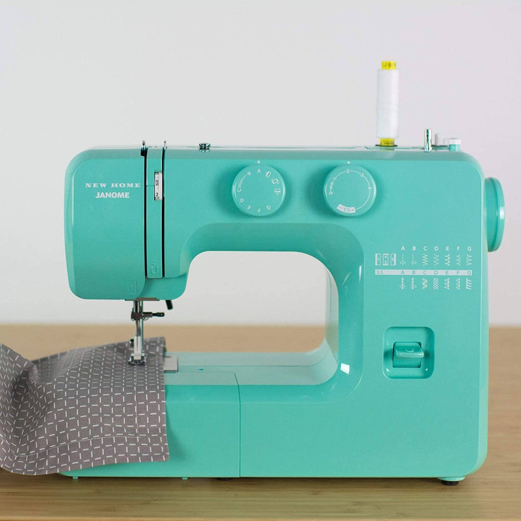 Turquoise sewing machine, front view with two stitch dials and needle area