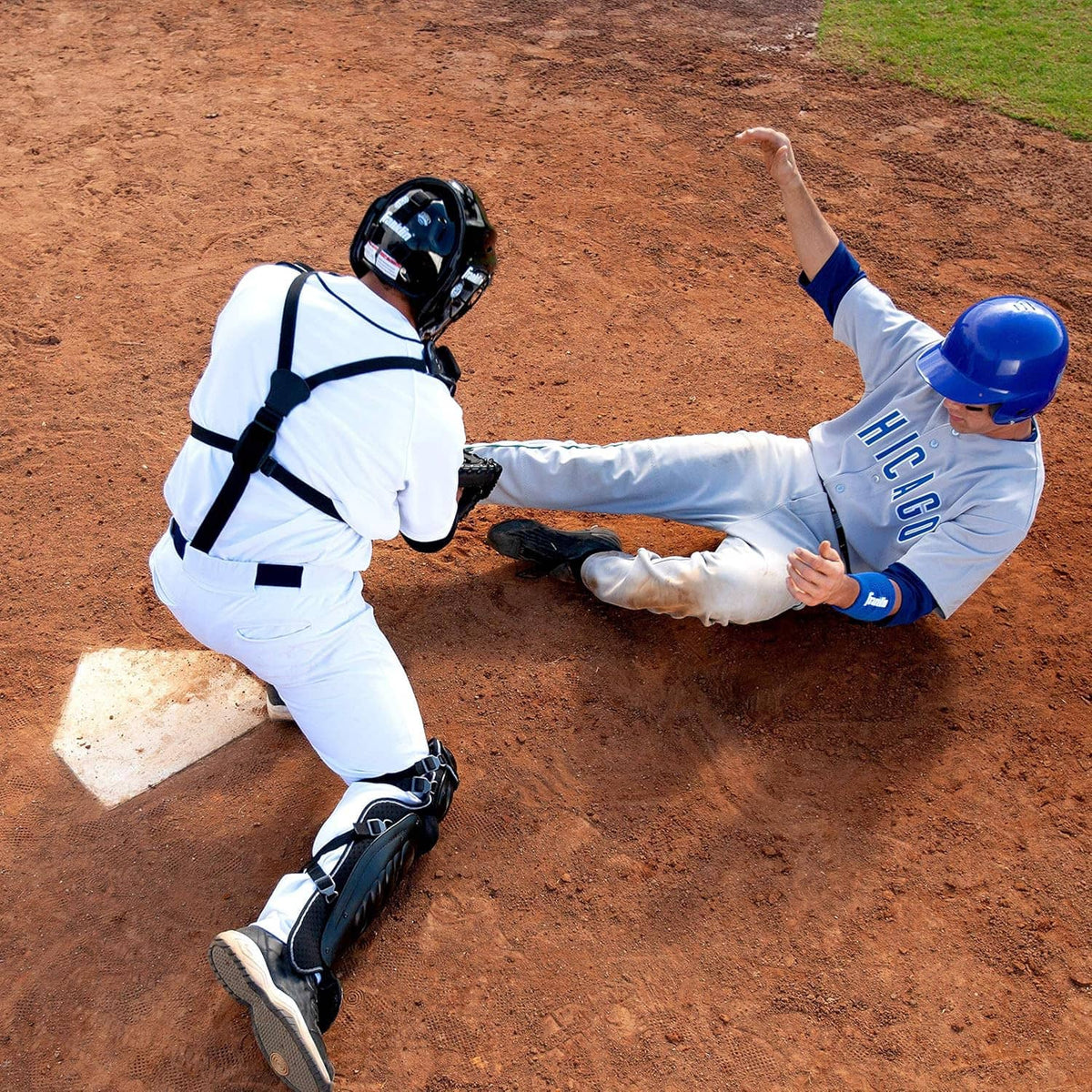 White rubber home plate on dirt during baseball practice with players nearby.