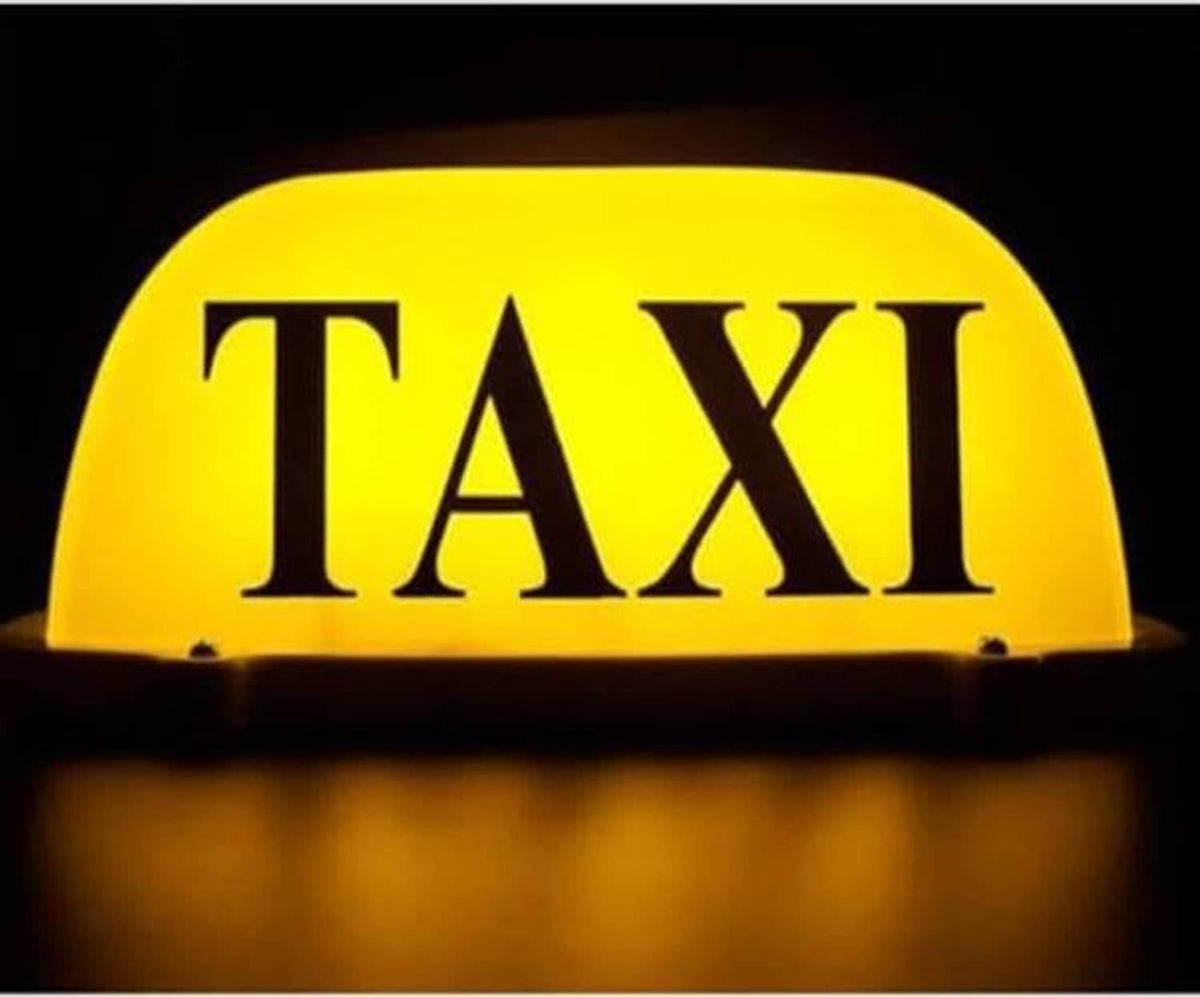 Lit yellow taxi roof light with large black TAXI letters on top