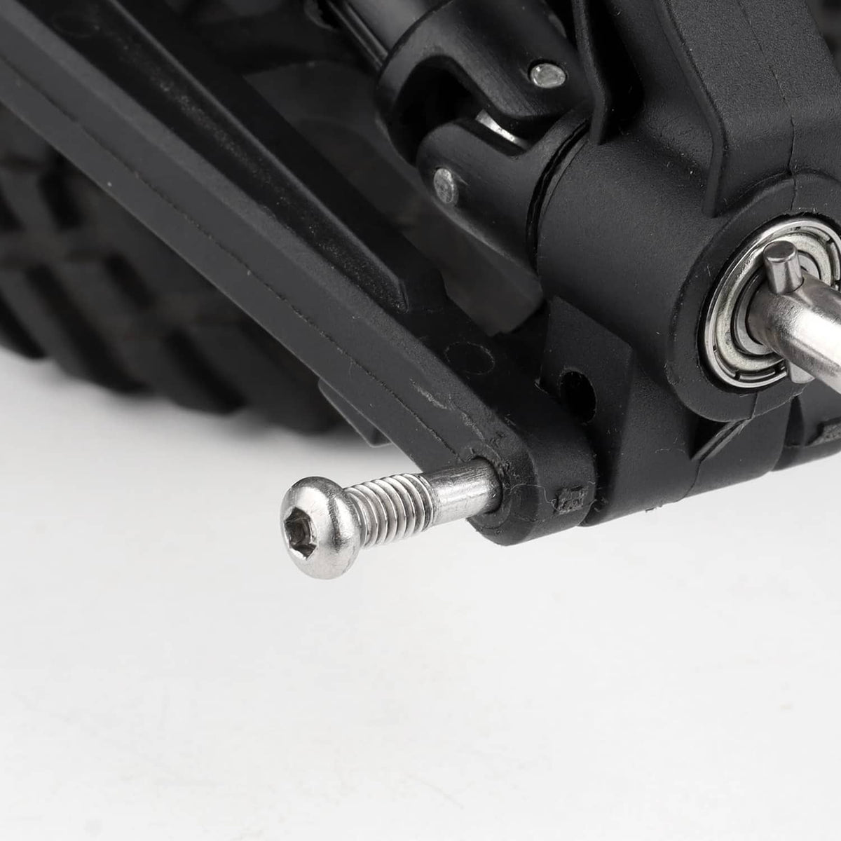 Close-up: silver threaded pin screw next to black suspension joint