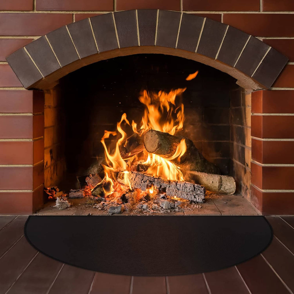 Black half-round fireplace mat on the floor in front of a brick firebox