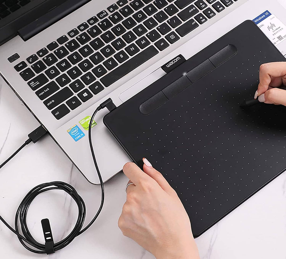 Hand plugging a micro USB cable into a tablet near the keyboard area.