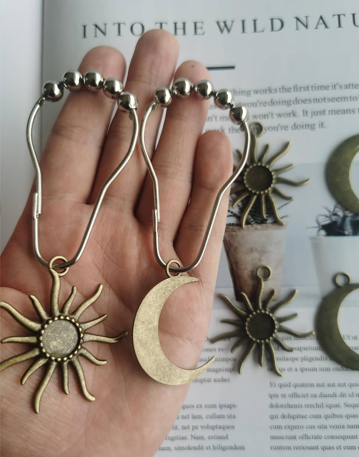 Hand holding metal shower curtain hooks with beaded rings and sun and moon charms