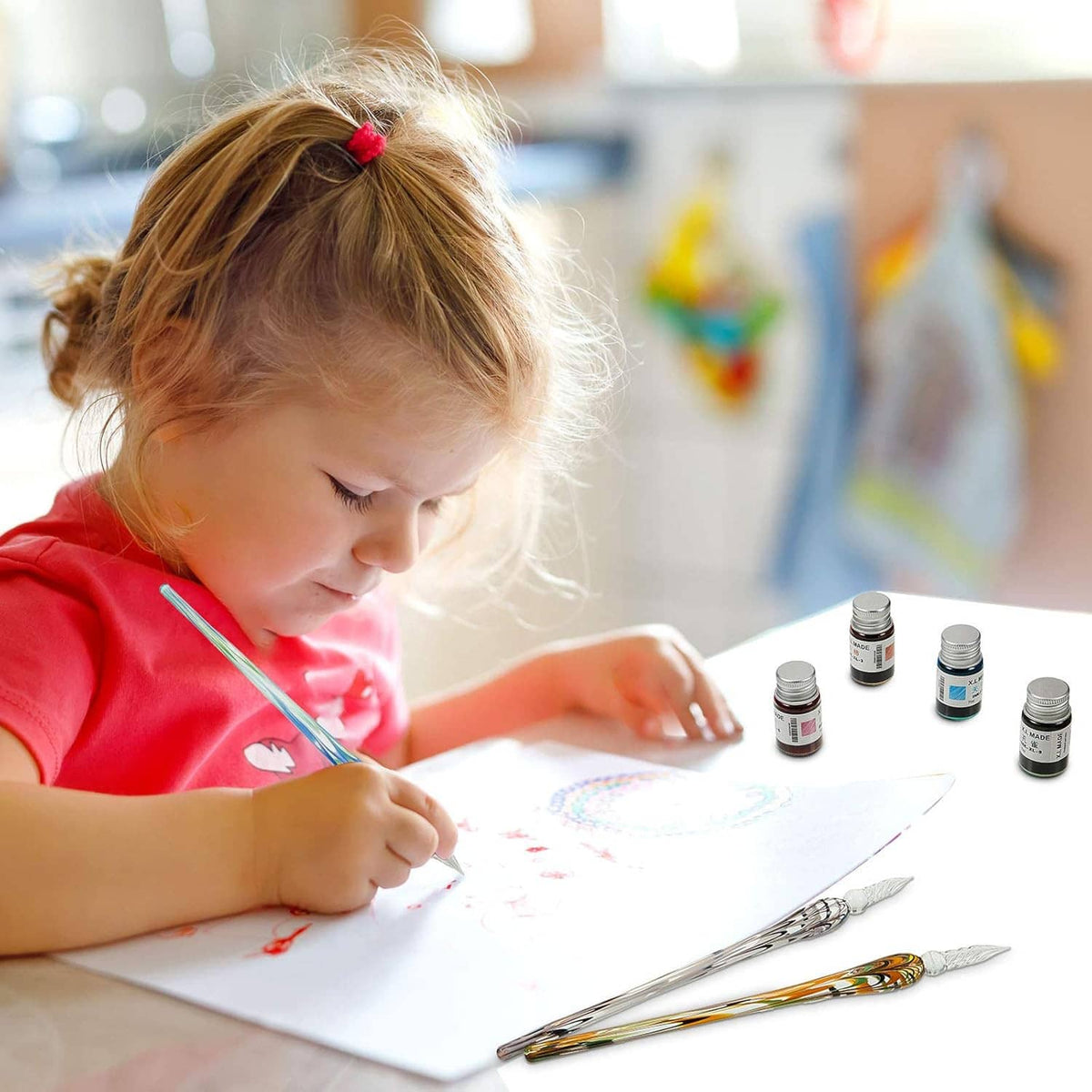 Glass dip calligraphy pen set used by a child writing on paper with small ink bottles