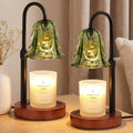 Green glass candle warmer lamp with black arch stand, glowing jar candle on wood base