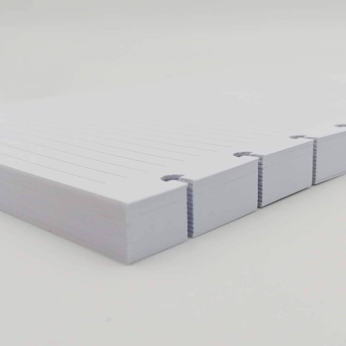 Stack of white lined A5 disc refill paper with blue edge binding marks