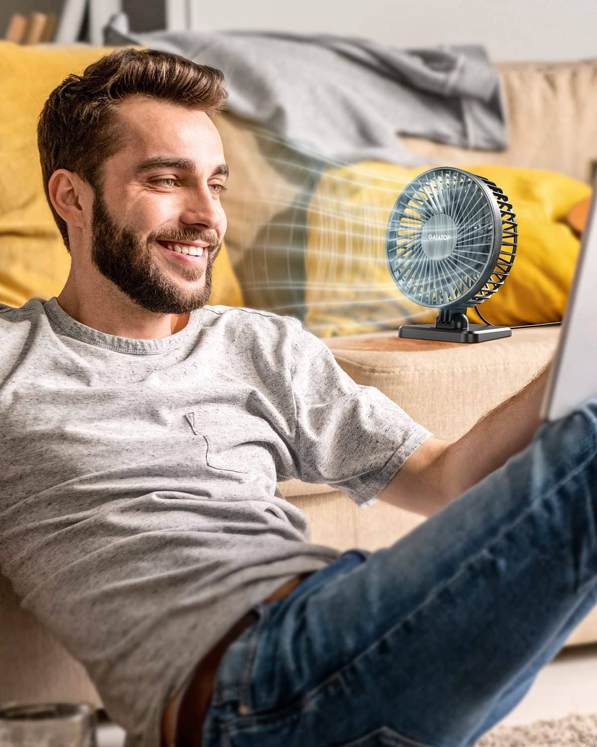 Black USB desk fan on table aimed toward a seated person on couch