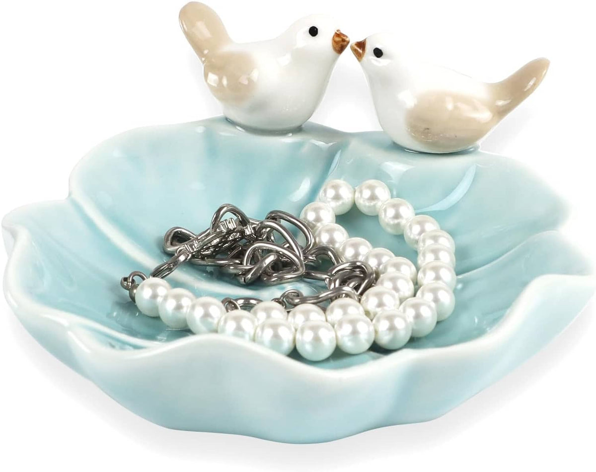 Ceramic lotus leaf jewelry tray with two white bird ring holders holding pearl bead necklaces