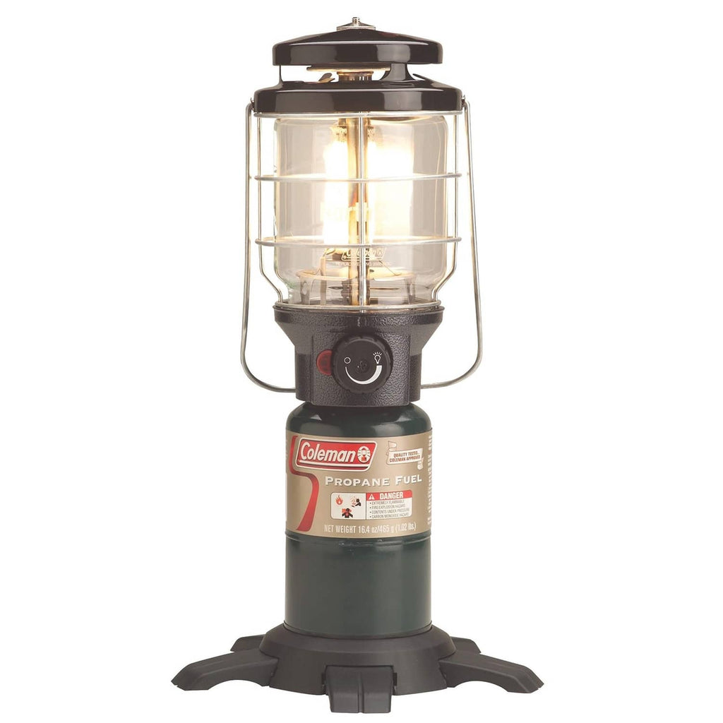 Coleman Northstar gas lantern with clear glass chimney, black base, and glowing burner flame