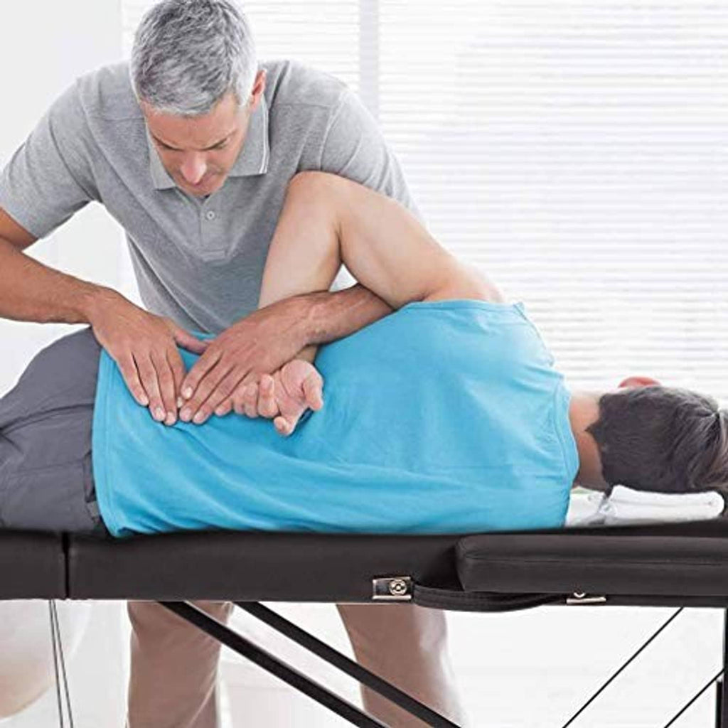 Black massage table with padded headrest during a back massage session