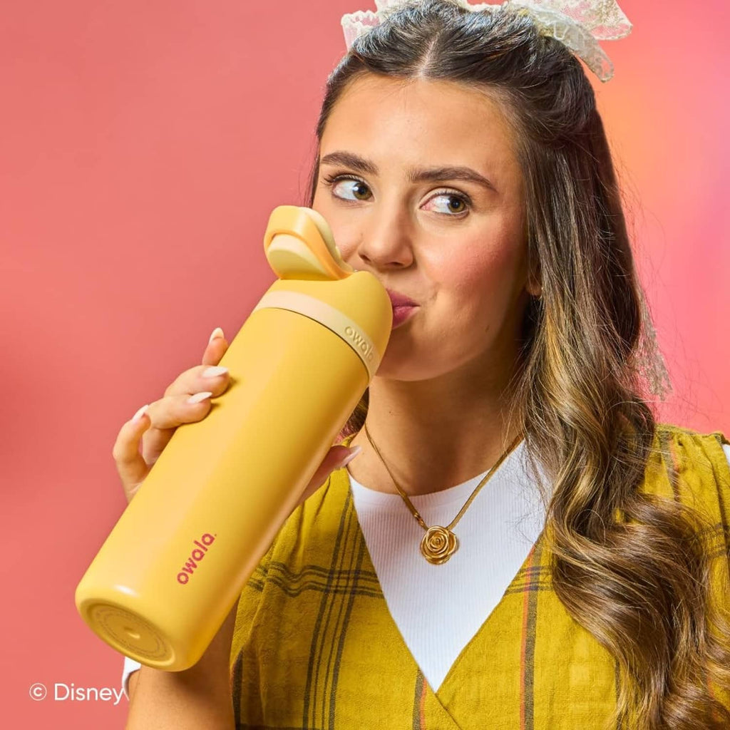 Woman sipping from a yellow insulated stainless steel FreeSip water bottle